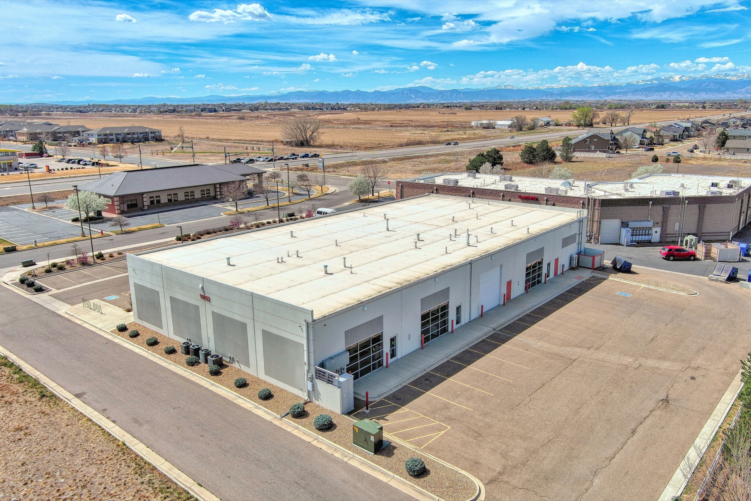 Aerial view of Leaf Coworking from the rear showing the full property, open fields, and Colorado Front Range mountains
