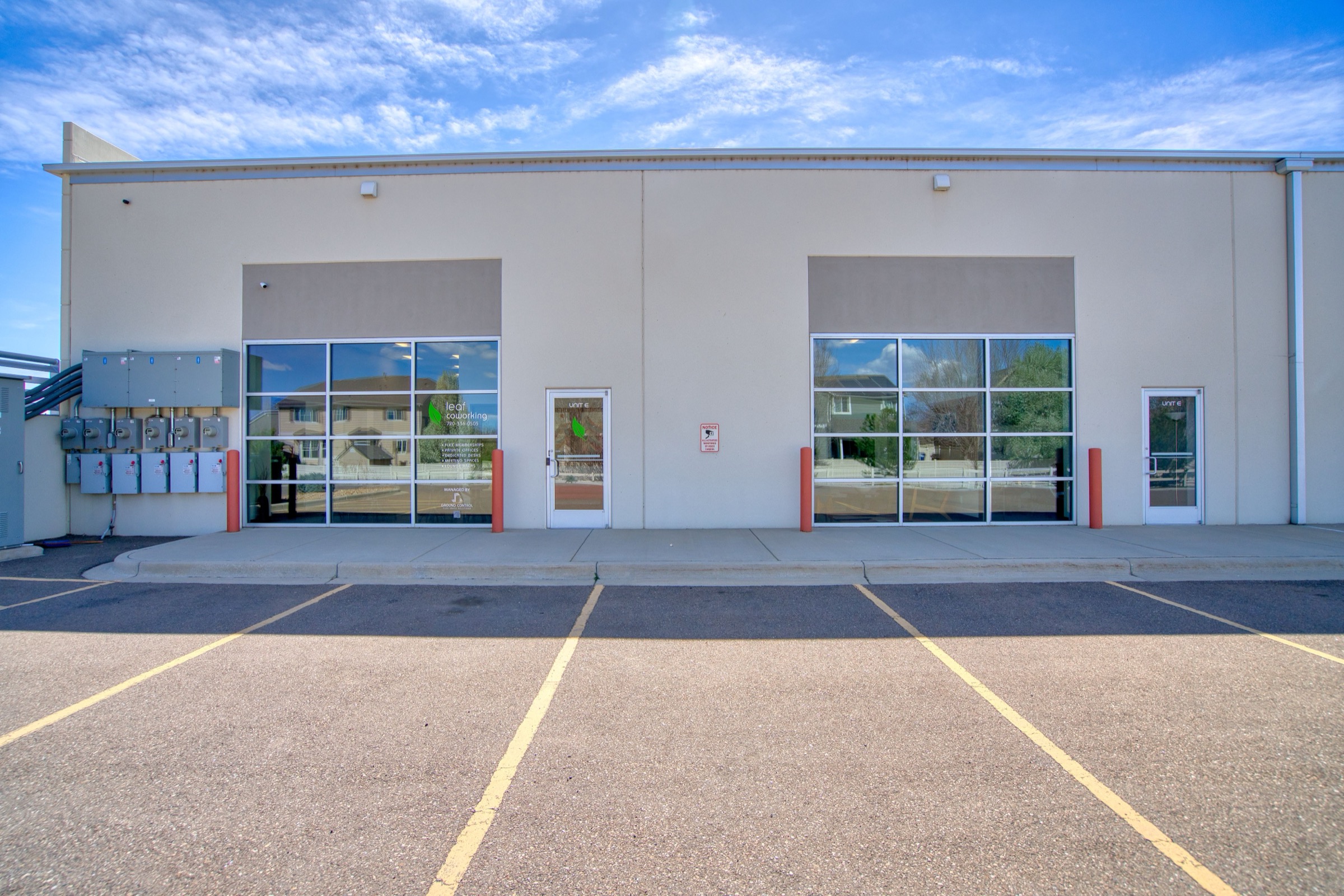 Side exterior of Leaf Coworking showing large floor-to-ceiling window bays with red accent trim