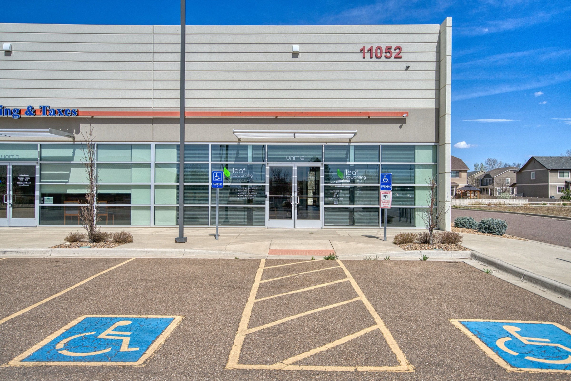 Street-level view of Leaf Coworking front entrance with glass storefront doors and accessible parking