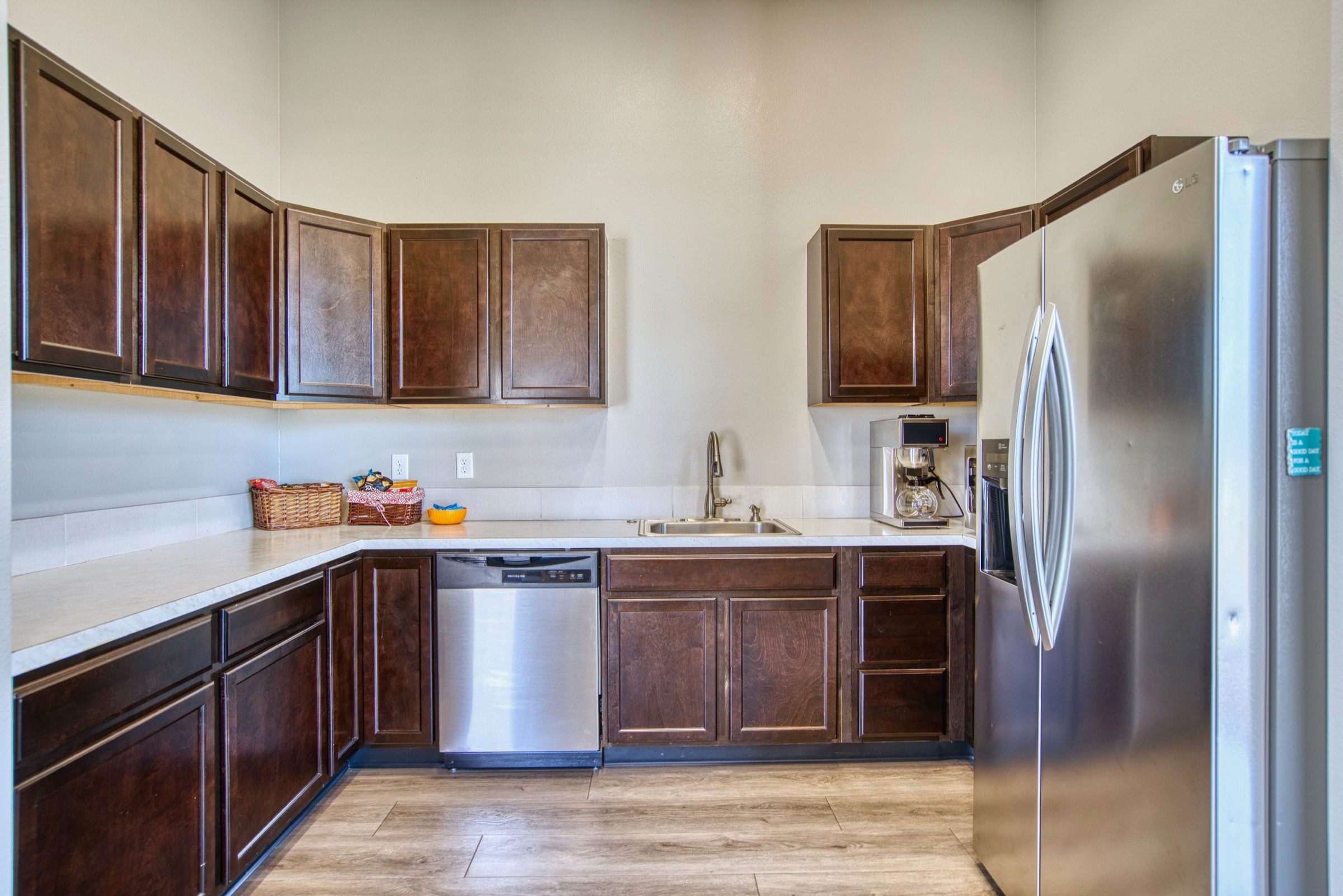 Full kitchen with dark wood cabinets, white quartz countertops, stainless steel refrigerator, dishwasher, and coffee maker