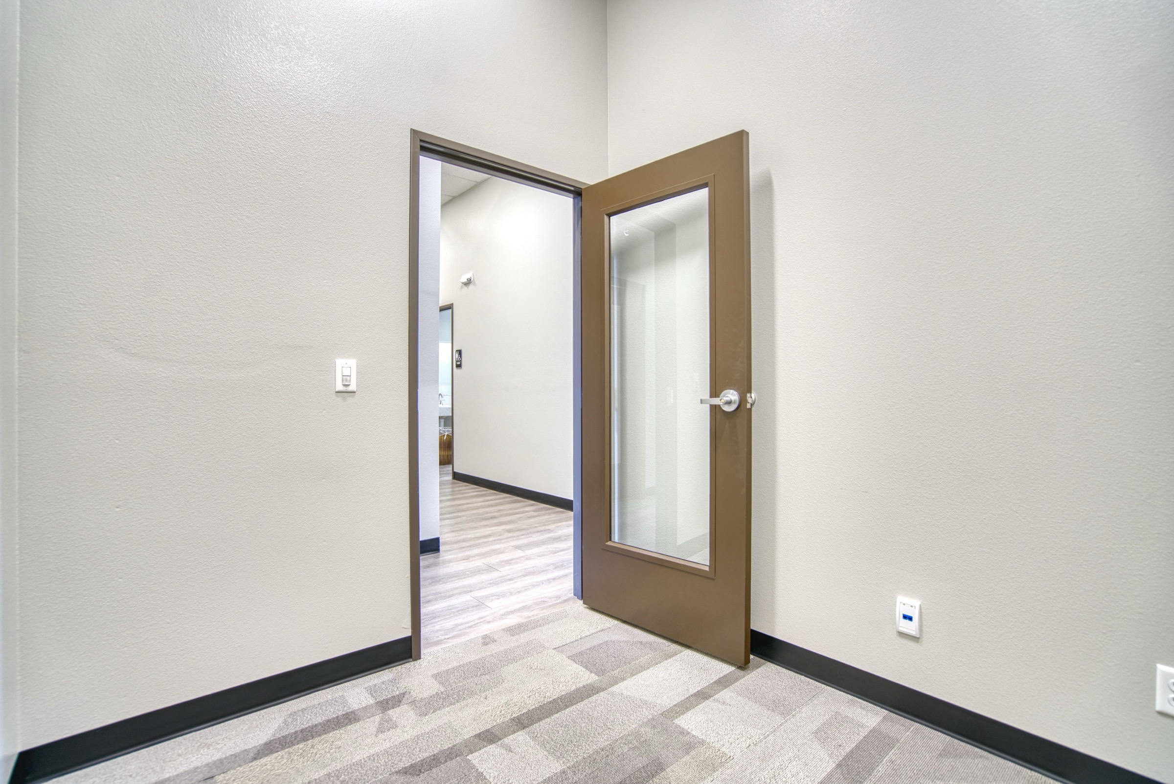 Compact private office with glass-paneled door, modern carpet tile, suitable for one to two people